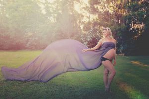 Pregnant Women with long purple fabric maternity photograph