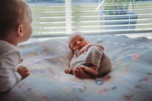 toddler-taking-a-moment-to-look-over-newborn-brothers-feet-Gold-Coast-Australia-newborn-inhome-documentary-photography