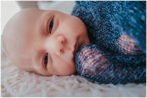 Wrapped-newborn-boy-looking-straight-into-camera-with-sweet-smile-gold-coast-inhome-photography