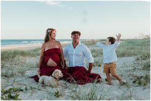 Beautiful-full-bloom-pregnant-woman-with-her-partner-toddler-and-puppy-on-the-sand-dunes-at-the-spit-gold-coast-maternity-photography