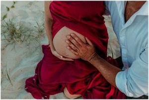 Beautiful-full-bloom-pregnant-woman-with-her-partner-and-puppy-on-the-sand-dunes-at-the-spit-gold-coast-maternity-photography