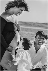 Beautiful-full-bloom-pregnant-woman-with-her-partner-toddler-and-puppy-on-the-sand-dunes-at-the-spit-gold-coast-maternity-photography
