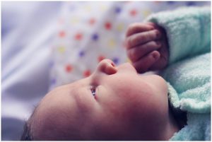 Sweet-newborn-putting-fingers-to-mouth-whilst-looking-outward-pindara-newborn-gold-coast-family-documentary-photography