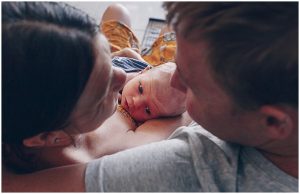 Parents-give-each-other-a-big-smile-while-cuddling-their-newborn-son-gold-coast-newborn-documentary-photograph