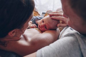 Parents-relaxing-on-couch-loving-on-newborn-son-dad-has-gentle-hand-on-babys-head-gold-coast-documentary-newborn-photography