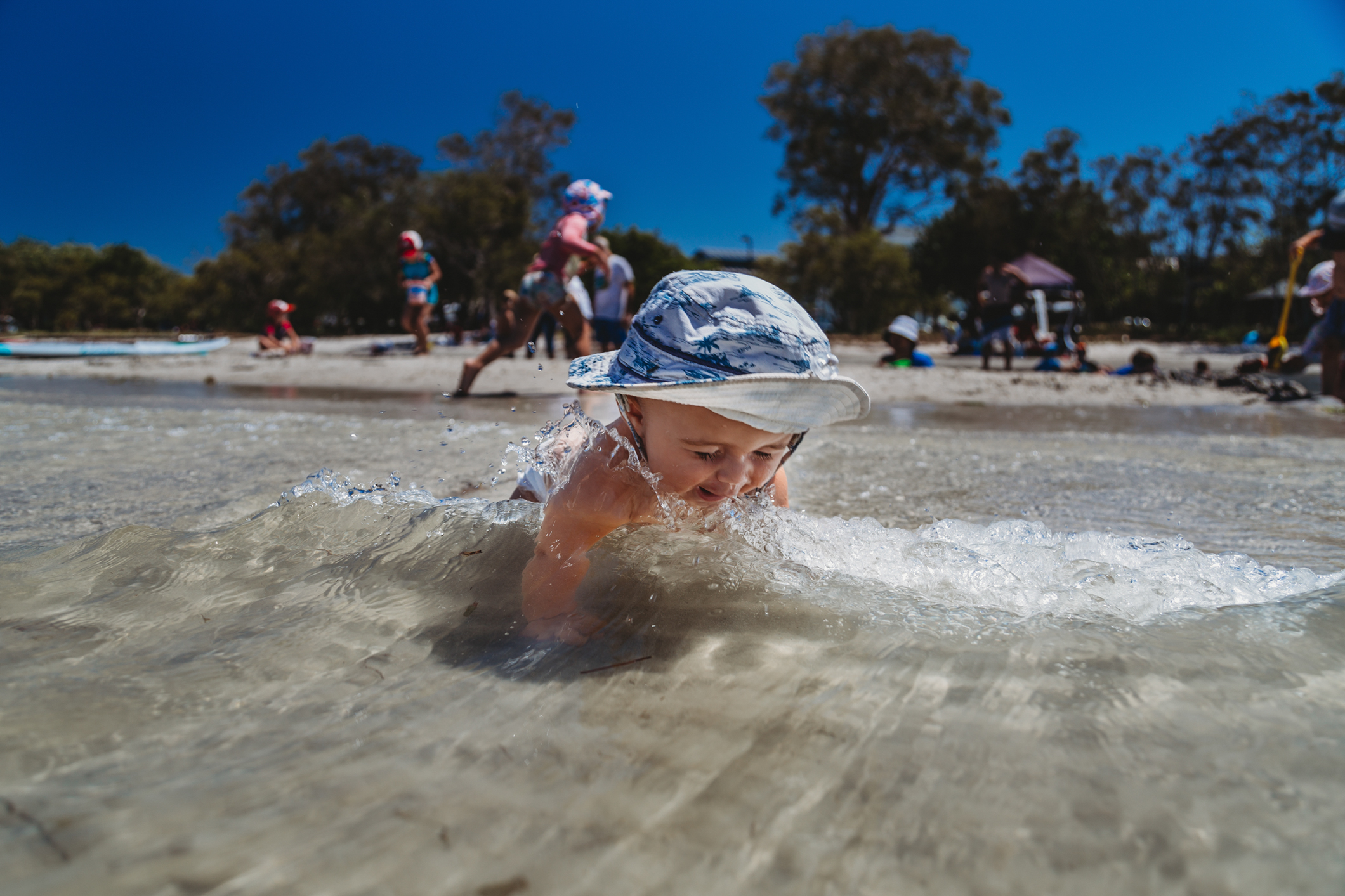 Baby-crawling-towards-the-water-at-the-beach-as-awave-approaches-gold-coast-family-documentary-photography