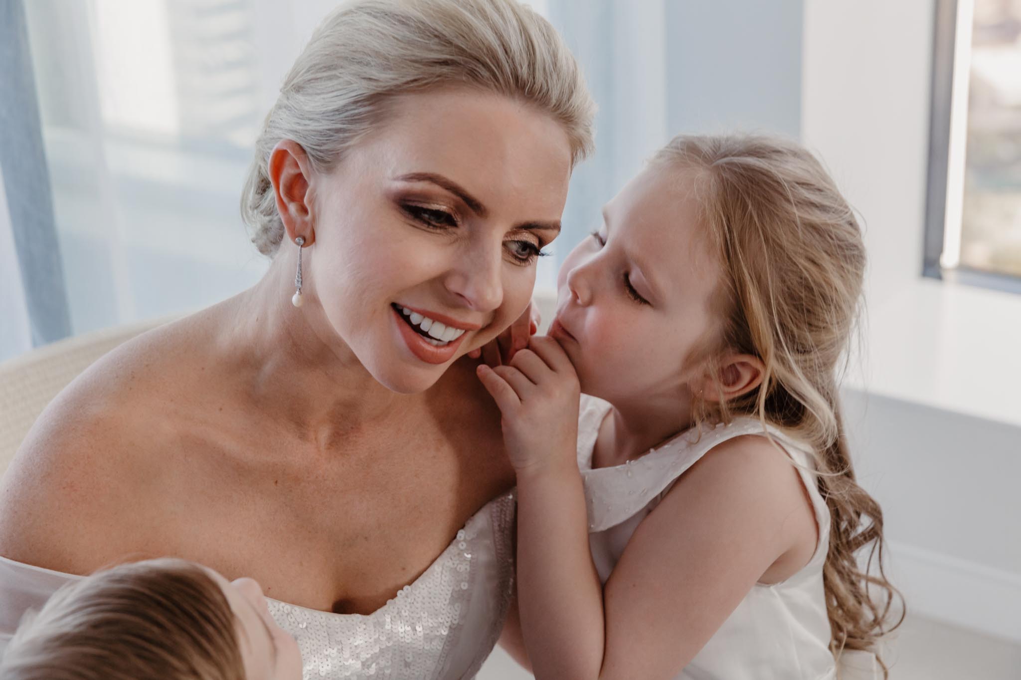 Preparing-to-walk-down-the-aisle-on-her-wedding-day-this-stunning-bride-is-given-last-minute-kisses-and-cuddles-from-her-beautiful-children-gold-coast-family-documentary-wedding-photography