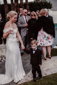page-image-a-beautiful-bride-takes-the-hand-of-her-toddler-son-and-provides-comfort-during-the reception-of-her-wedding-beautiful-intimate-mother-and-son-moment-gold-coast-family-documentary-wedding-photography
