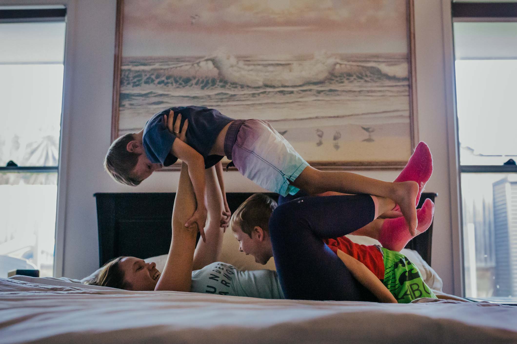 blog-image-Two-kids-jumping-on-the-bed-with-mum-in-front-of-painting-that-was-their-grandmas-part-of-a-remembering-mum-series-gold-coast-australia-family-documentary-photography