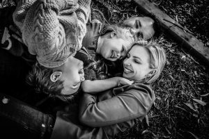 a-family-having-a-cuddle-puddle-on-the-ground-at-the-park,laughing-and-giggling-as-part-of-their-gold-coast-family-short-story-telling-photography-sessio