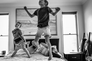Two-kids-jumping-on-the-bed-with-mum-in-front-of-painting-that-was-their-grandmas-part-of-a-remembering-mum-series-gold-coast-australia-family-documentary-photography