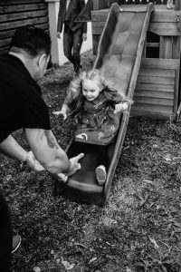 young-girl-coming-down-slide-into-the-strong-hands-of-her-dad-gold-coast-family-short-story-telling-photography