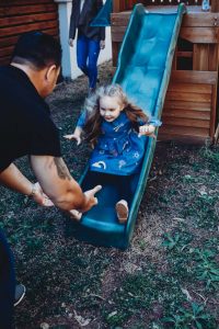 young-girl-coming-down-slide-into-the-strong-hands-of-her-dad-gold-coast-family-short-story-telling-photography-in-colour