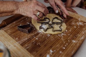 Grandma-making-christmas-shortbread-with-her-4-grandkids-using-cookie-cutters-to-shape-cookies
