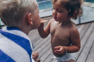 toddler-feeding-her-brother-a-biscuit-after-swimming-in-the-pool