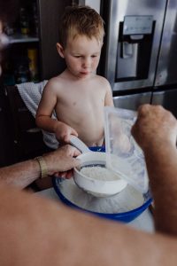 young-boy-shifting-flour-making-christmas-shortbread-with-grandma