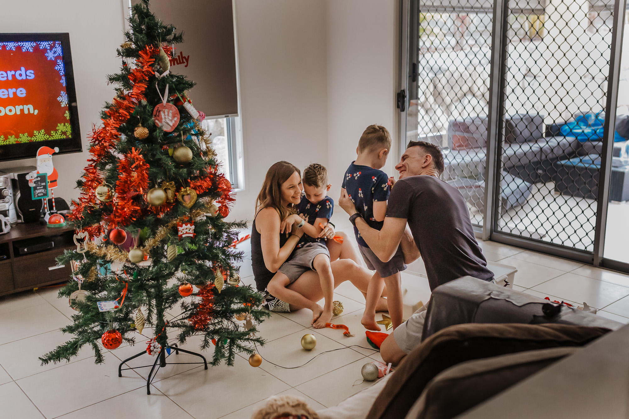 Parents playing on the floor with their children as they put up their Christmas tree
