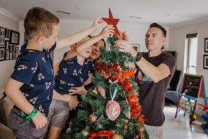mum dad and their two sons putting the star on top of the Christmas tree