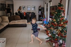 four year old son has a little dance moment as the family finish putting up the Christmas tree and placing all the present underneath