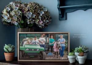 View of a metal print cased in a oak frame of a family participating in the Gold Coast this is who we are yard portraits, showcasing their family including their dog and their laughing horse