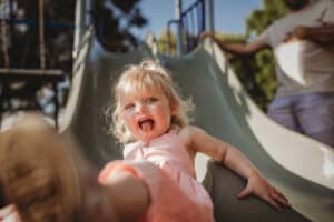 Small-girl-coming-down-a-slide-with-her-tongue-poked-out laughing